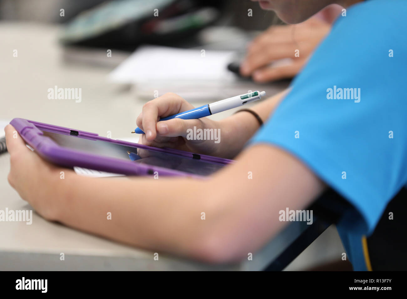 Student using a purple tablet digital information technology tool devise to reseach during class time lesson at a modern high school education educati Stock Photo