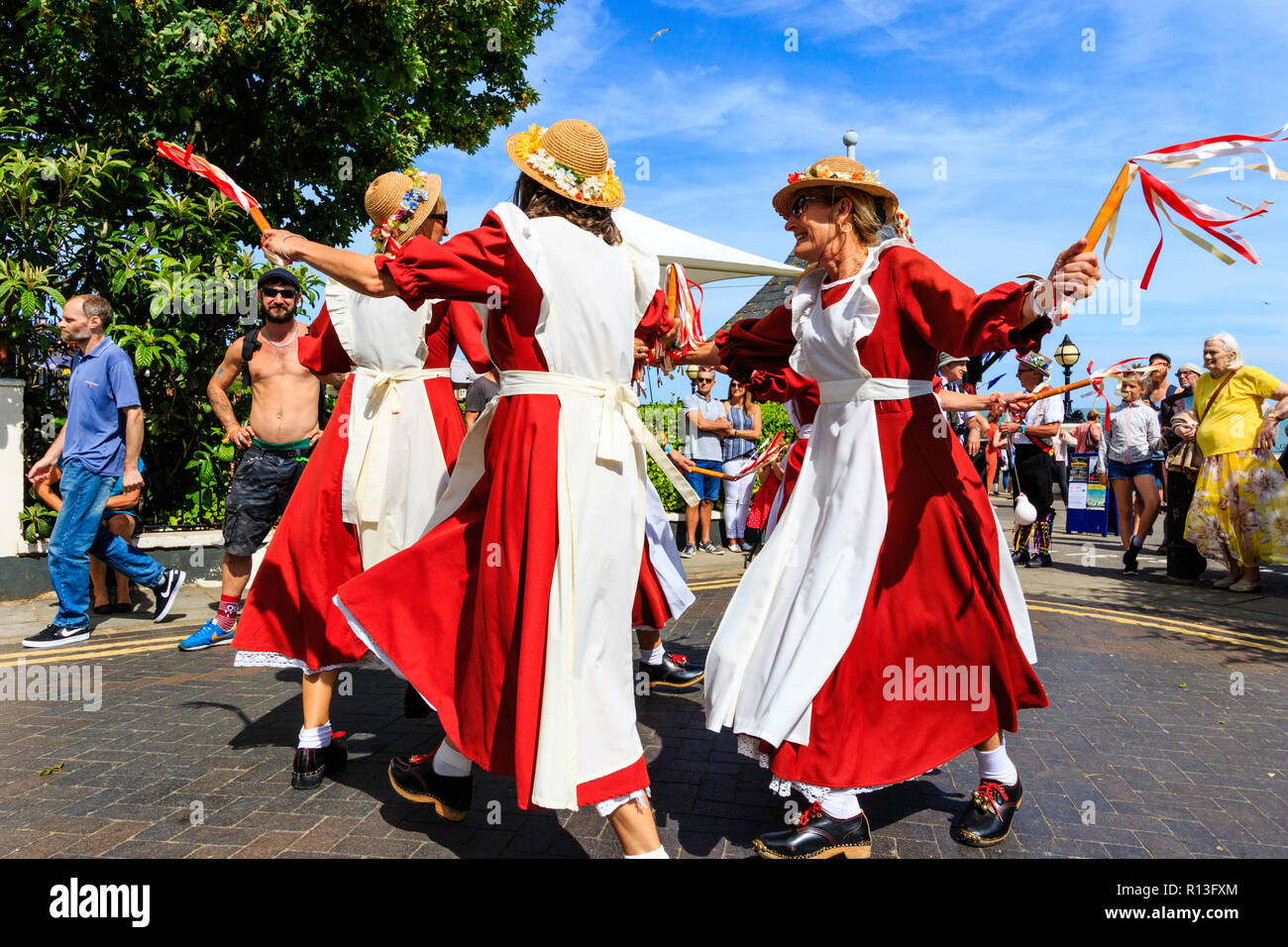 Broadstairs Folk Week festival. English folk dancers, the women's Rising Larks Morris side dancing in the street in their orange and white costumes. Stock Photo