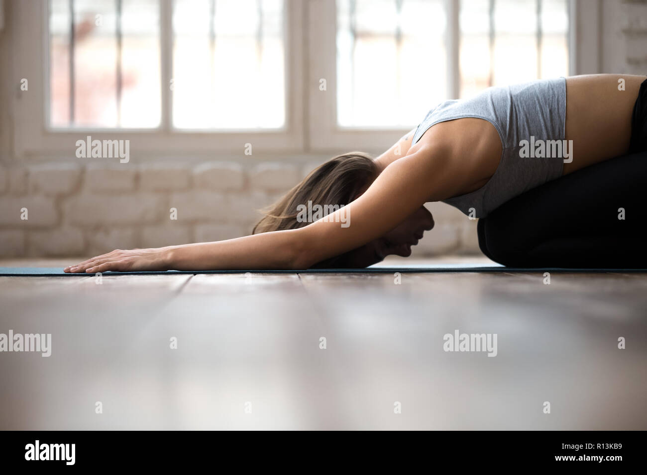 Young sporty woman practicing yoga, doing Child exercise, Balasa Stock Photo