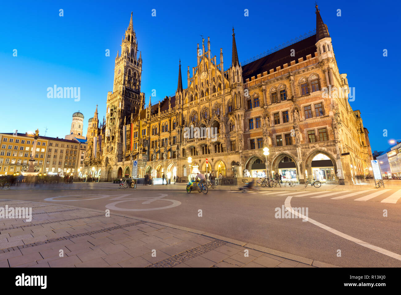 People walking at Marienplatz square and Munich city hall in night in Munich, Germany. Cafes, bars, shops and restaurants. Motion blurred people. Stock Photo