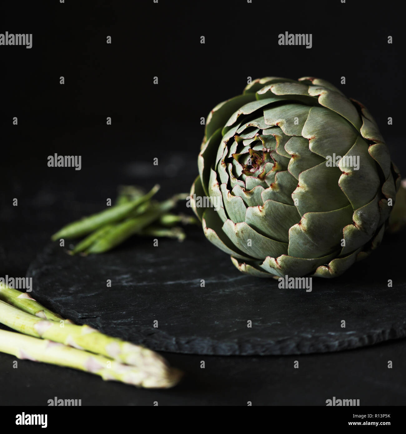 Artichoke with asparagus and green beans at black background Stock