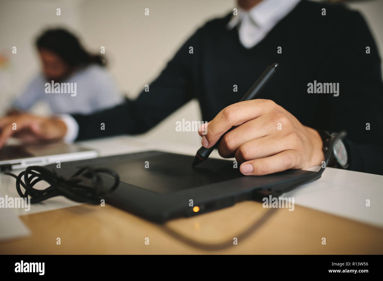 Close up of a man writing on a digital writing pad using a digital pen. Tech savvy man using modern gadget to input data. Stock Photo
