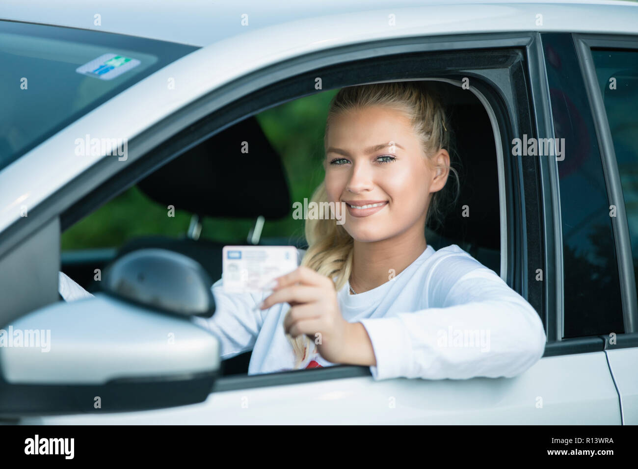 Driving school. Attractive young woman proudly showing her drivers license. Free space for text. Copy space. Stock Photo