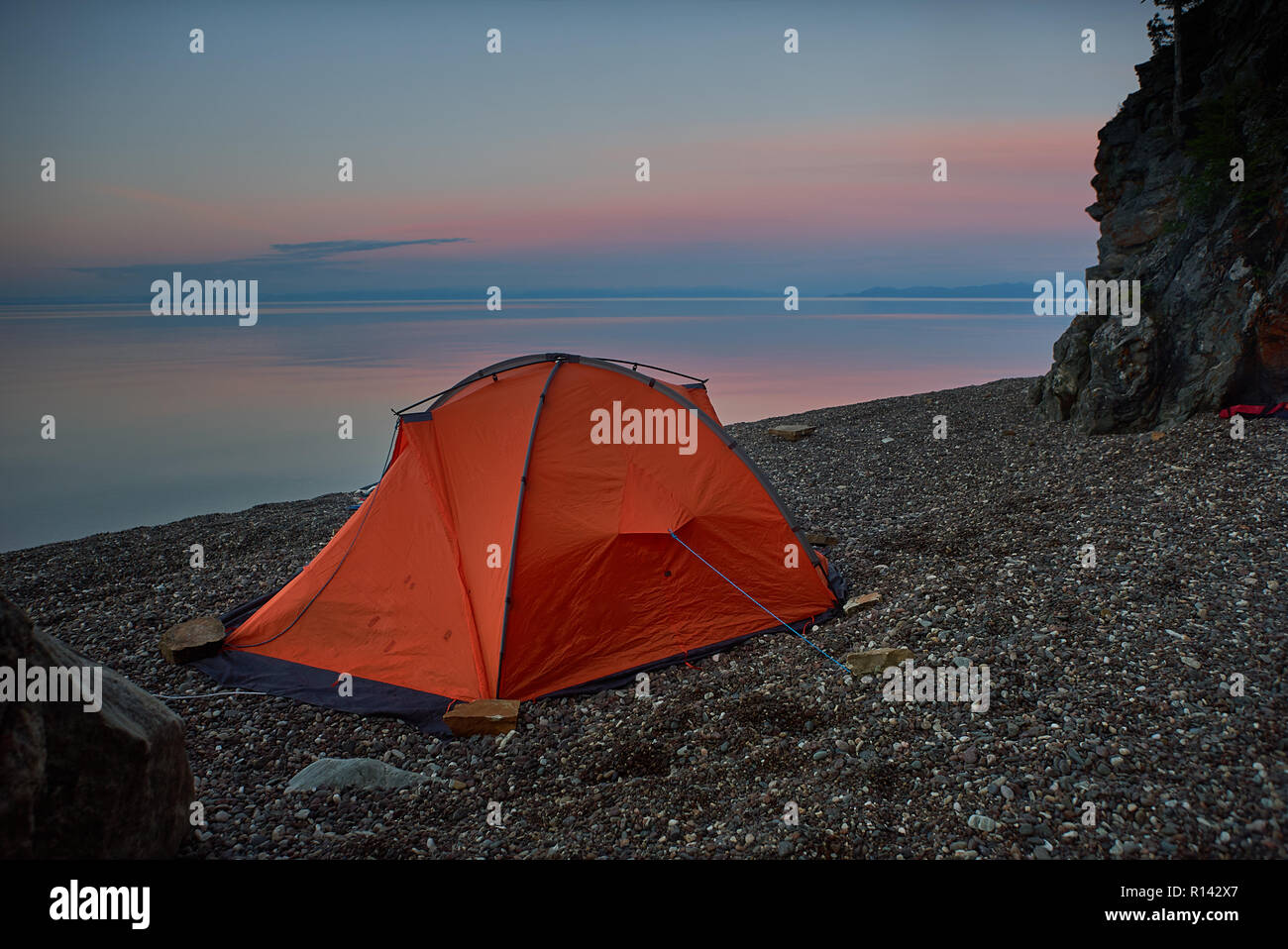 Tent near lake shore at the beautiful sunset Stock Photo