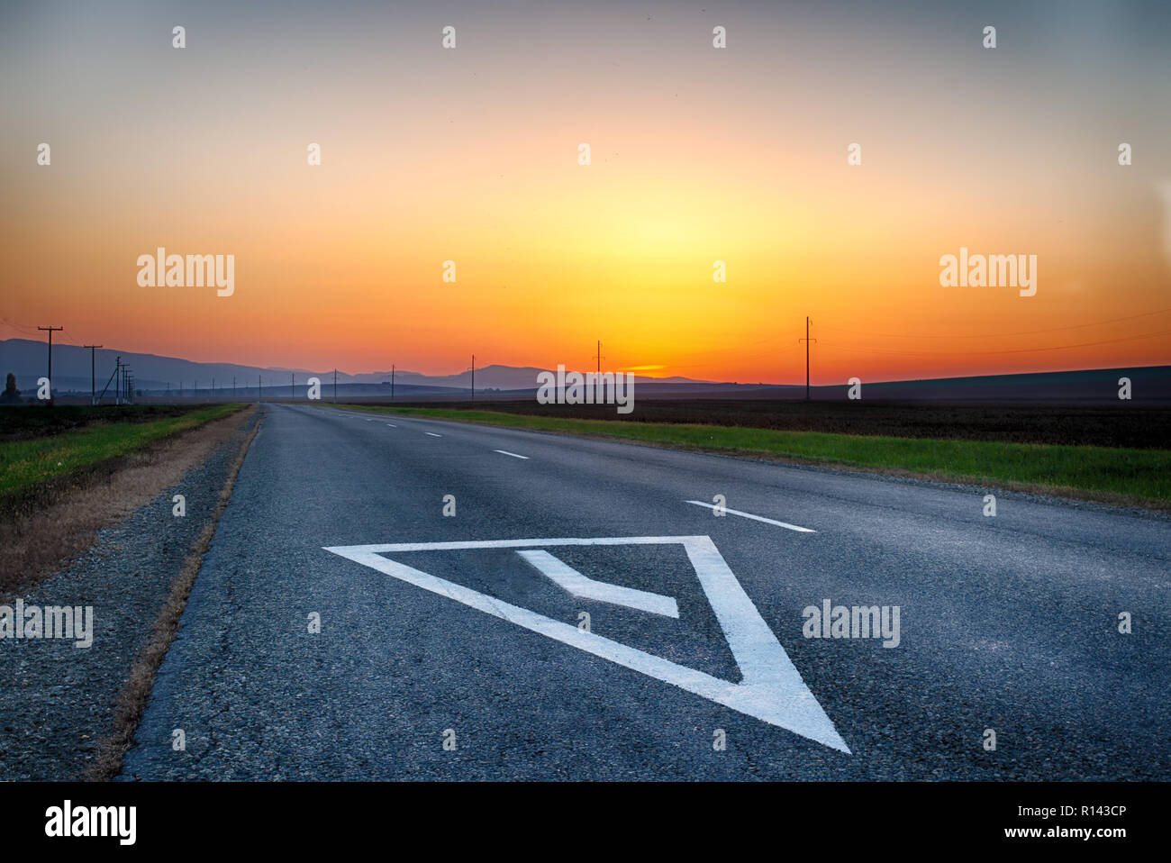Mountain road. The curve of the road at sunset. Asphalt coating. Bright horizon. Stock Photo