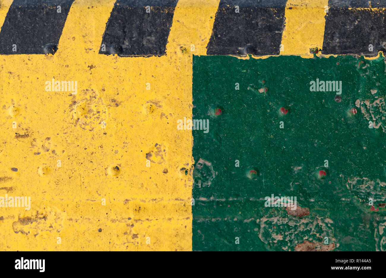 Striped yellow black caution pattern over green grungy steel industrial wall Stock Photo