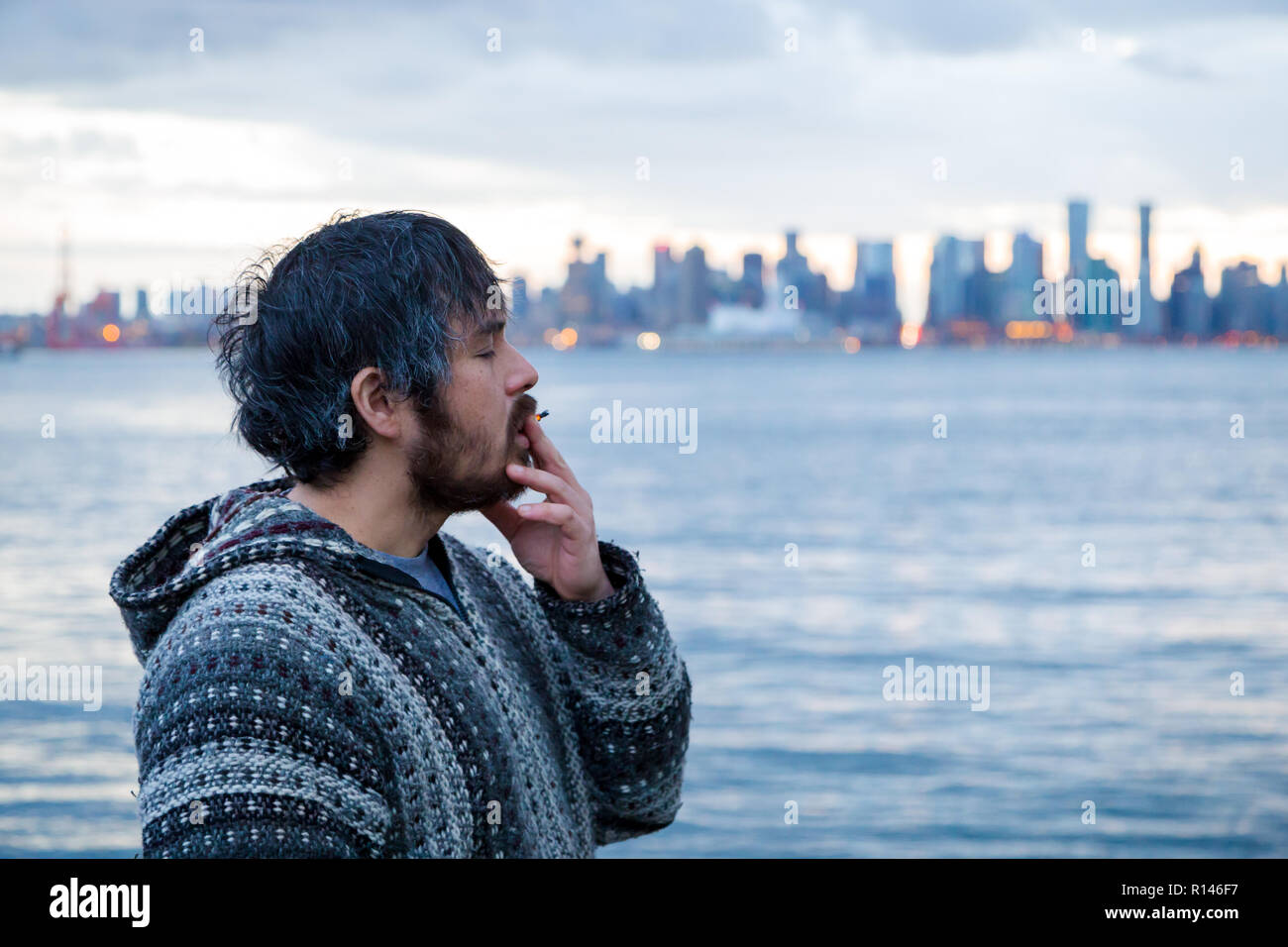 A young man smoking a joint with downtown Vancouver, BC, in the background shortly after Canadian marijuana legalization. Stock Photo