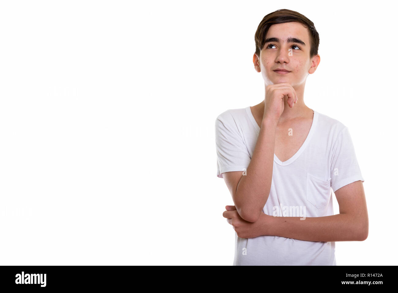 Studio shot of young handsome Persian teenage boy thinking while Stock Photo
