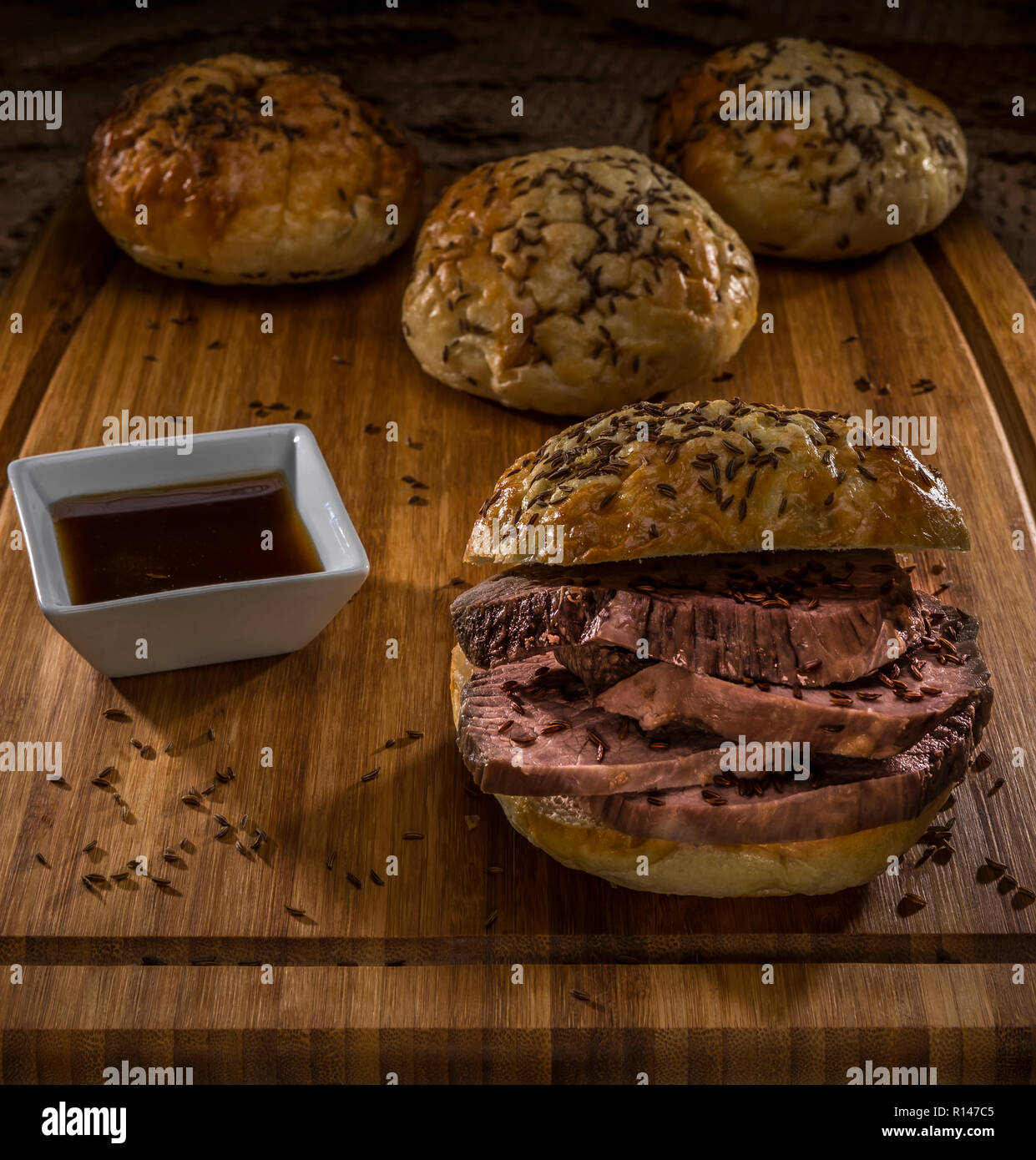 roastbeef on kimmelweck roll on wooden cutting board with au jus Stock