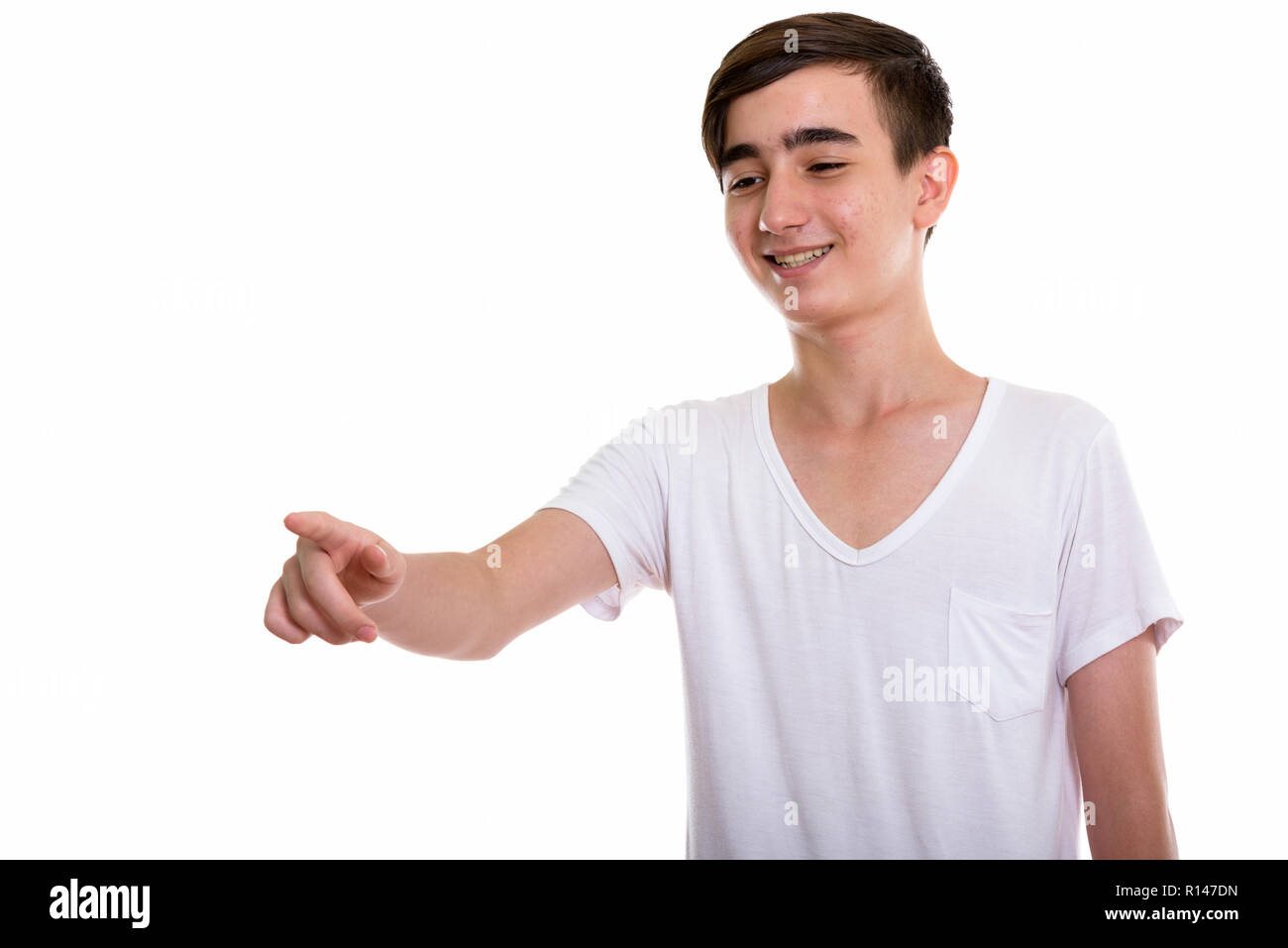 Studio shot of young happy Persian teenage boy smiling and laugh Stock Photo