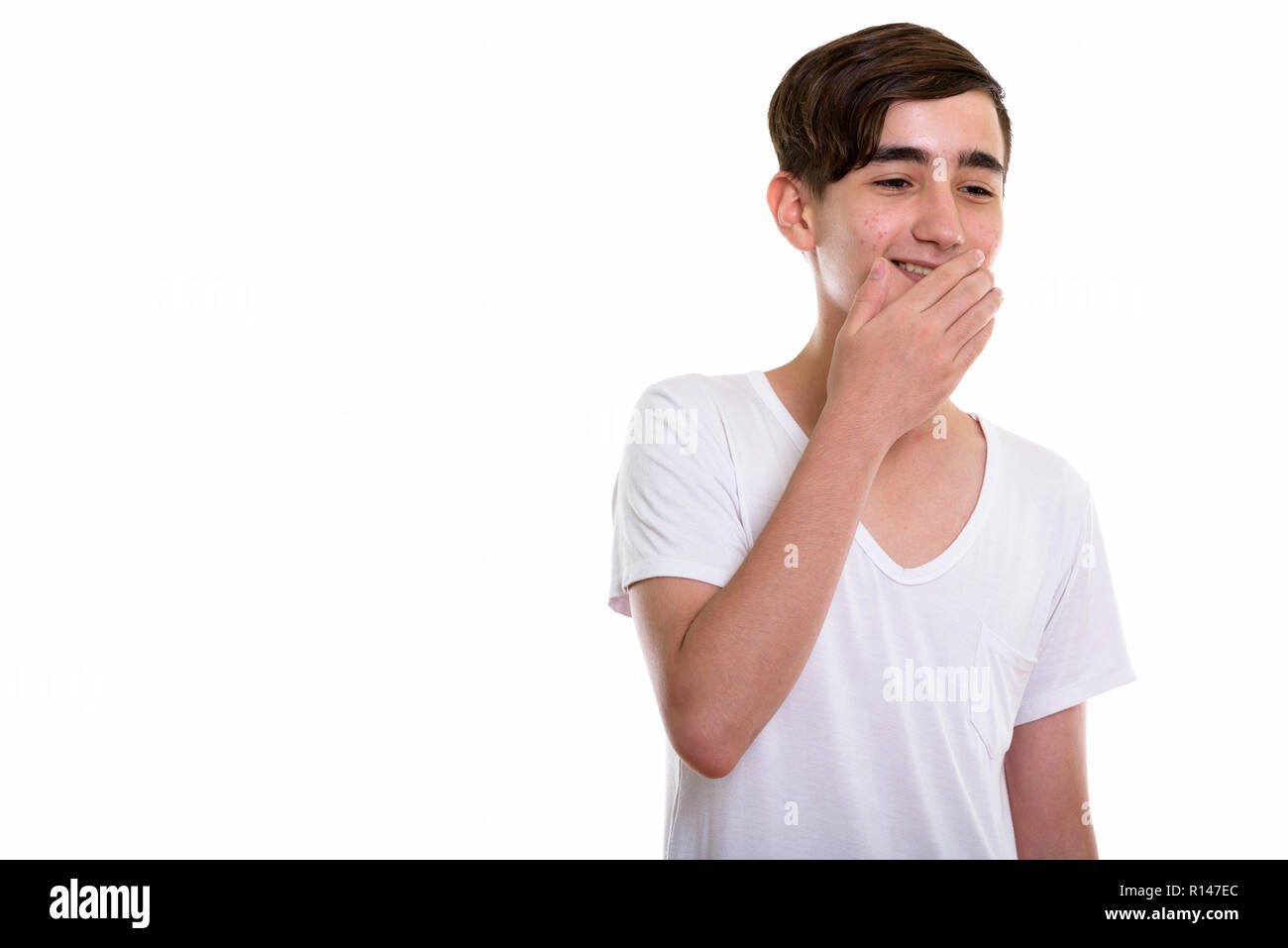 Studio shot of young happy Persian teenage boy smiling and giggl Stock Photo