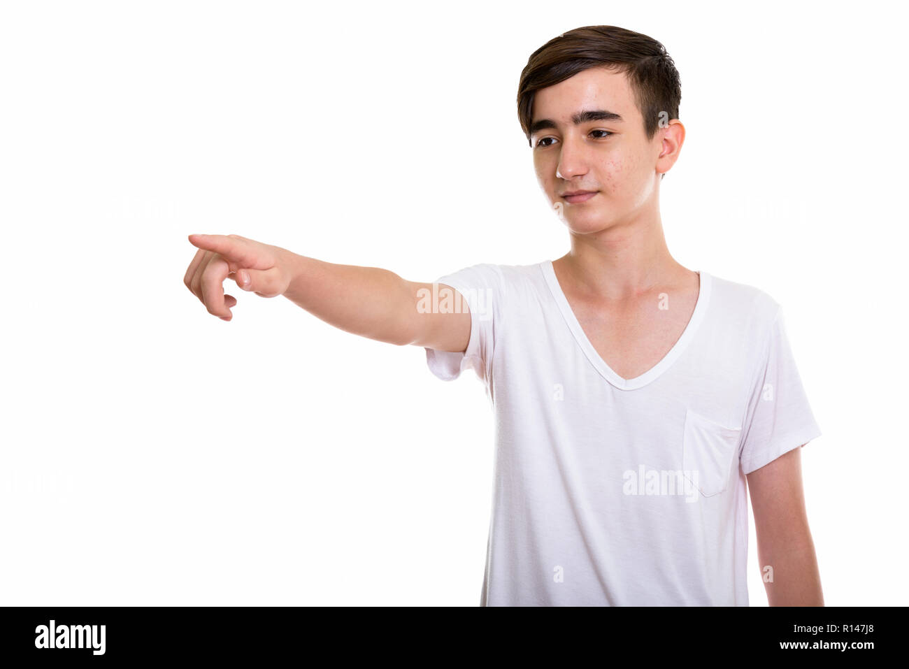 Studio shot of young handsome Persian teenage boy pointing and l Stock Photo