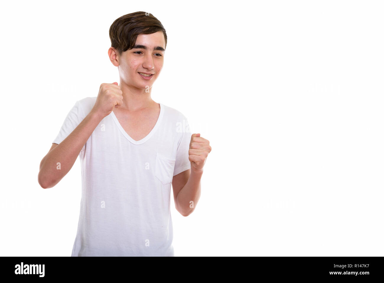 Studio shot of young happy Persian teenage boy smiling while get Stock Photo