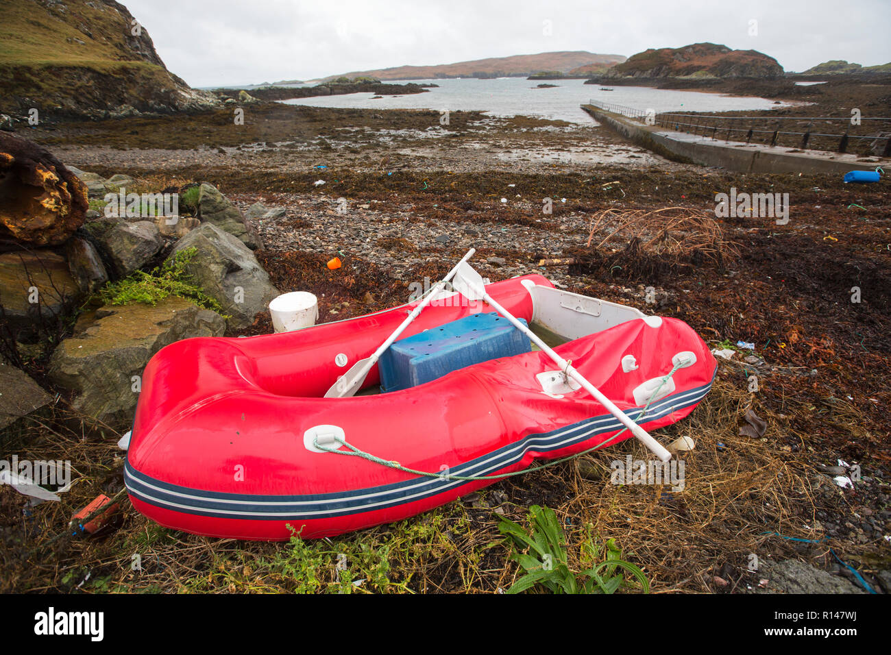 The slipway for the ferry to Handa Island at Tarbet, Sutherland, Scotland, UK with a punctured rib and plastic rubbish on the foreshore. Stock Photo