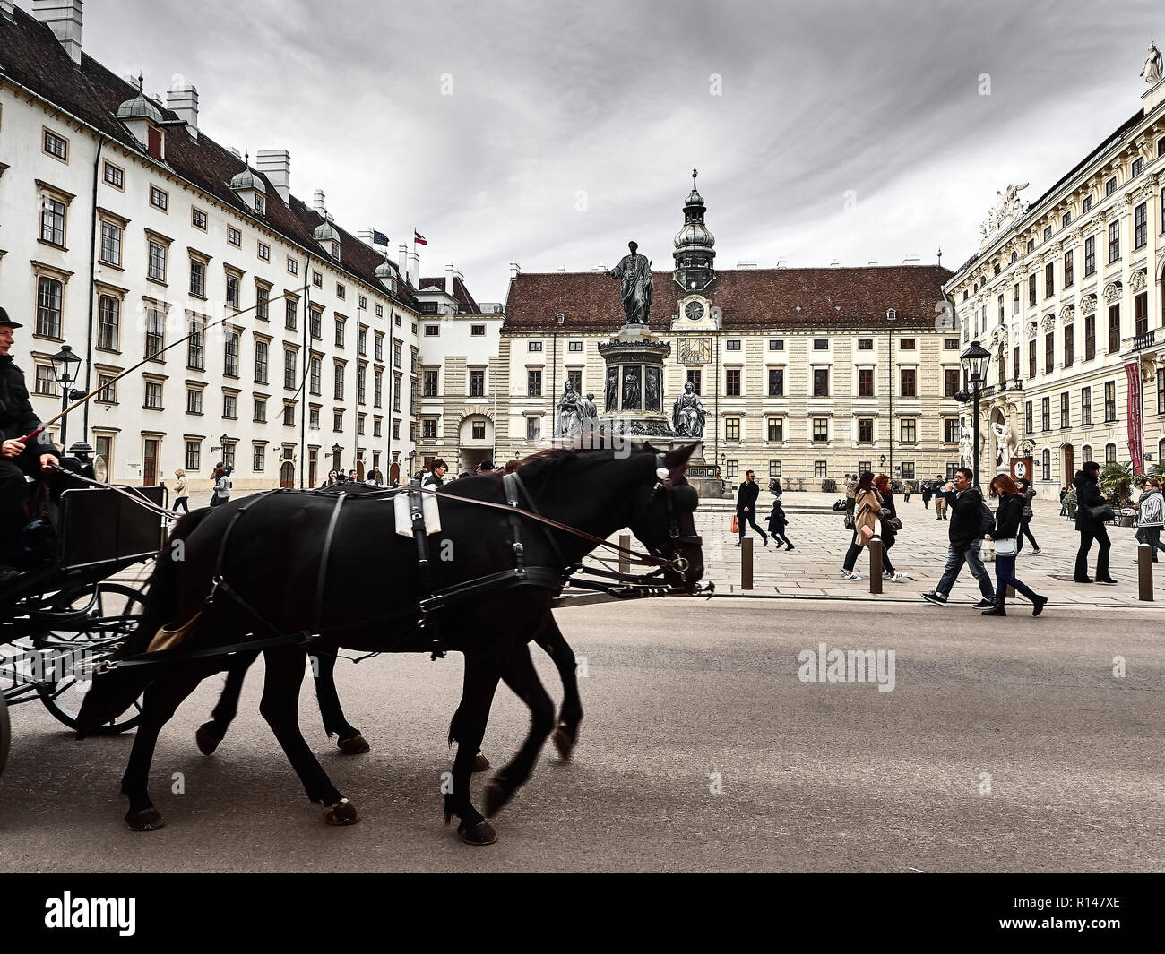 Vienna, Austria - November 1, 2018 - A horse-drawn carriage passing inside the Hofburg palace. People are visiting the palace Stock Photo