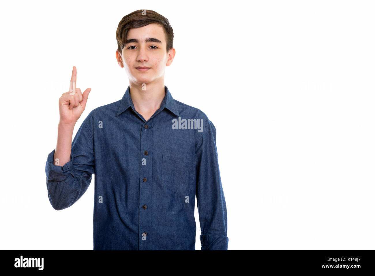 Studio shot of young handsome Persian teenage boy pointing finge Stock Photo