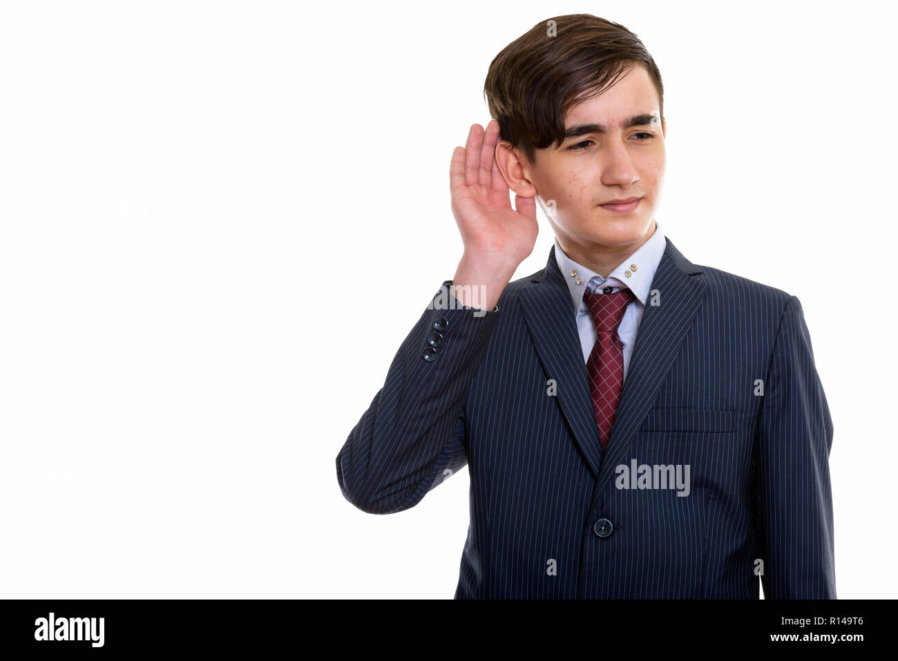 Studio shot of young handsome Persian teenage businessman listen Stock Photo