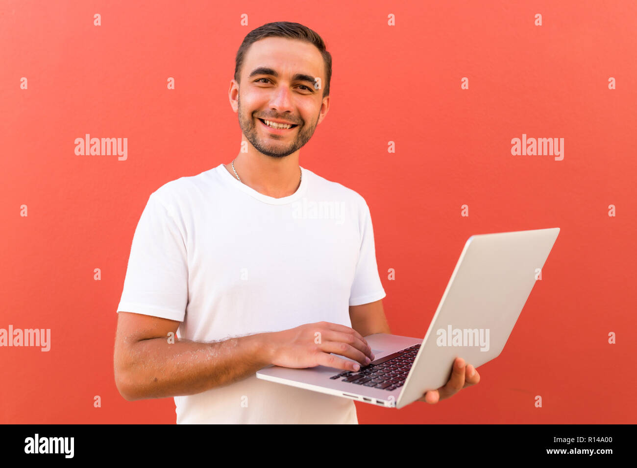 Handsome programmer with laptop on red background Stock Photo