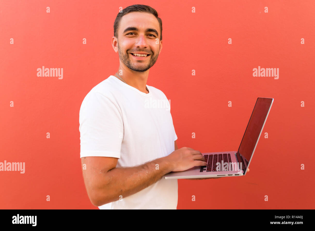 Handsome programmer with laptop on red background Stock Photo