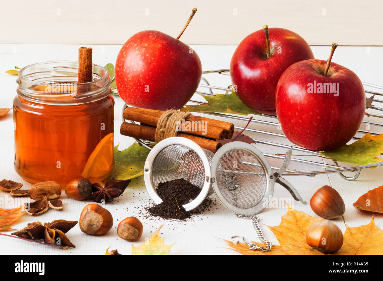 White wooden table with 2 glasses of tea with fall, autumn decoration and white background. Colorful leaves, lemon, cinnamon, walnuts, apples, tea, wa Stock Photo