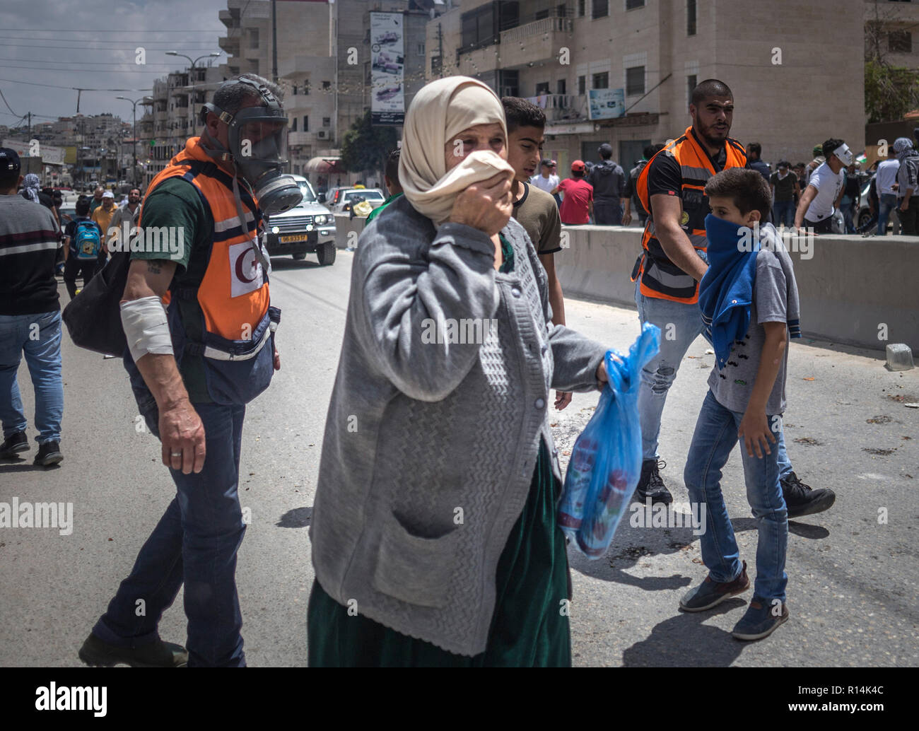 A woman seen covering her face after having inhaled tear gas fired by the Israeli army during the demonstration. As the US government moves the embassy to Jerusalem, thousands of Palestinians protest in Gaza and the West Bank the same day that marks the 70th anniversary of the Nakba. In Gaza, Israeli troops shot to death more than 58 people and injured 2,000 on that day. At Qalandiya military checkpoint hundreds marched and threw stones at Israeli soldiers, who responded with firing live bullets, rubber bullet and also tear gas. Stock Photo