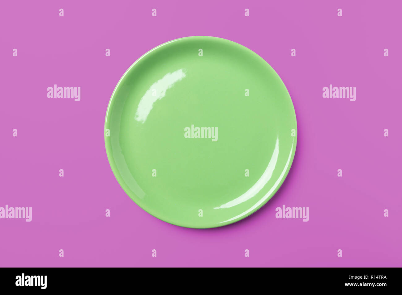 Green pastel plate on complementary pink background, pop art syle, view directly from above Stock Photo