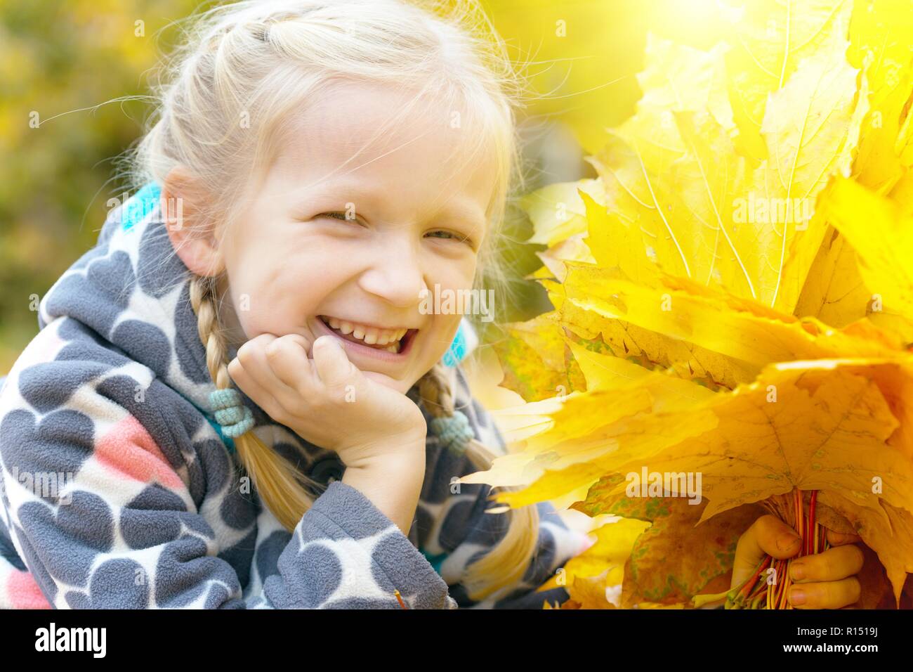 autumn - smiling little girl with a maple leaf on the street Stock ...