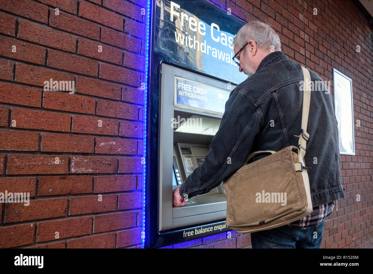 Swedish tourist makes a cash withdrawal in pounds from an ATM machine in Leeds. Stock Photo