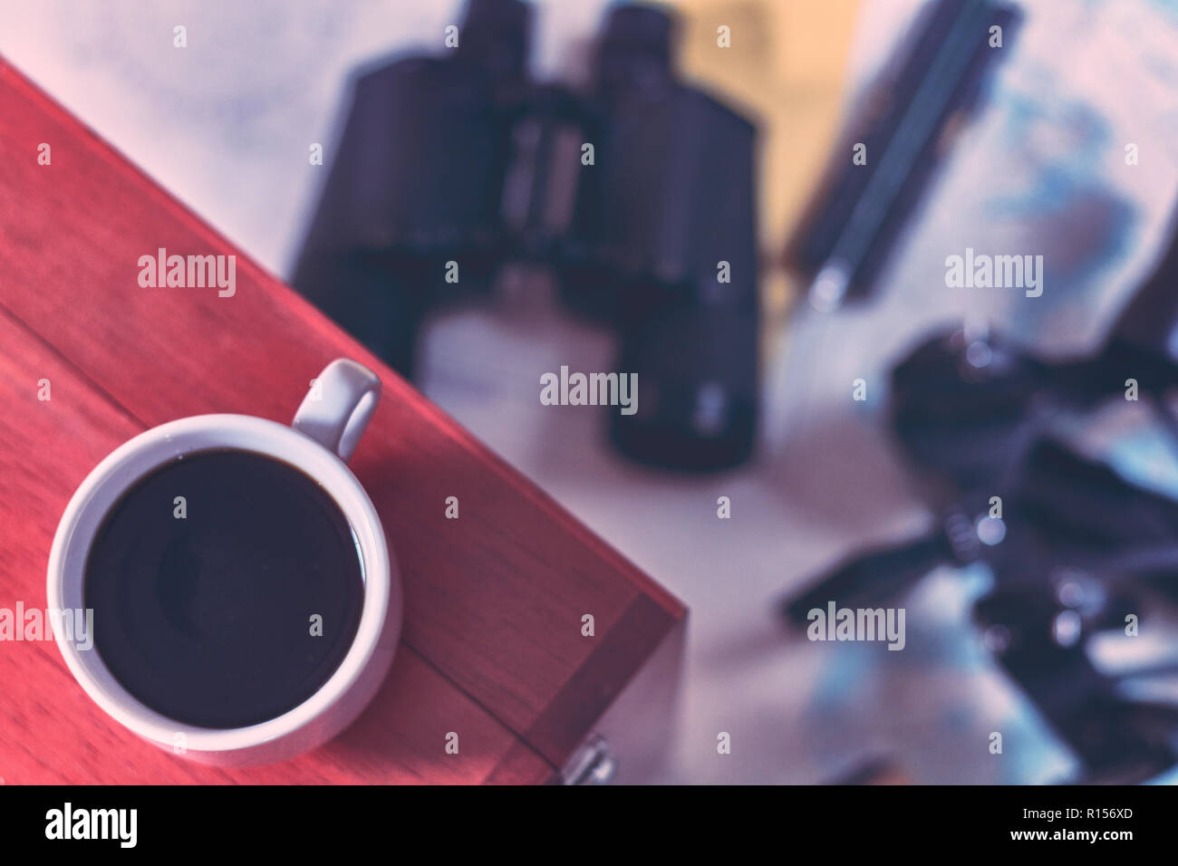 Background with cup of coffee and blurred binocular, pencil, marine sextant lying down on navigational chart. Stock Photo