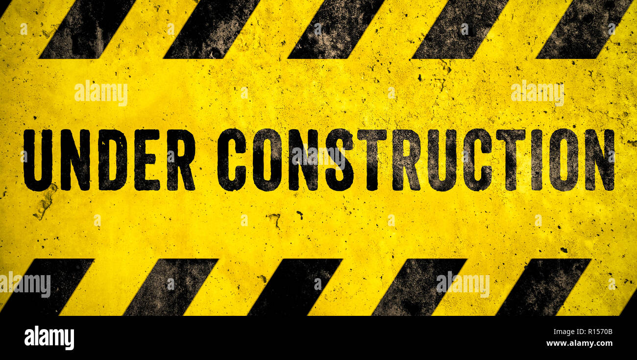 Under construction warning sign text with yellow black stripes painted ...