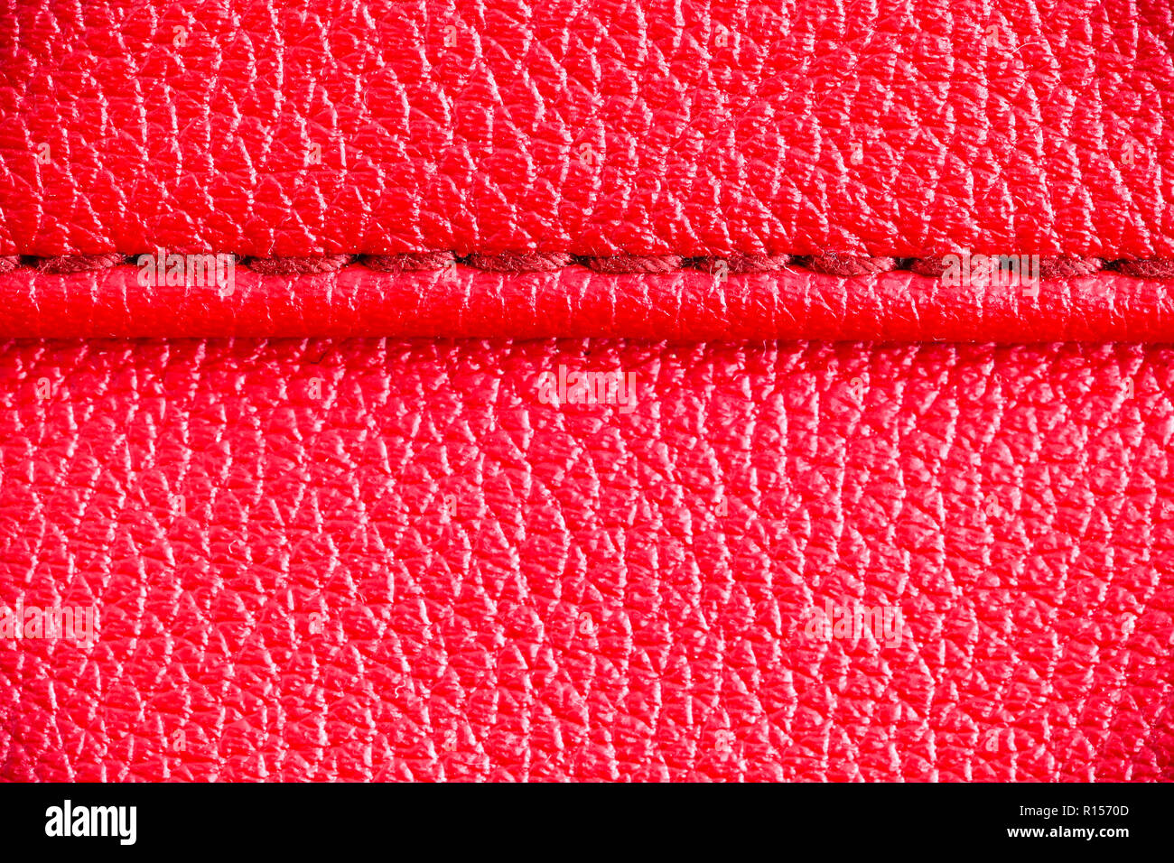 Two layers of red leather textile sewed stitched tightly together under high magnification close detail photography as surface texture background. Stock Photo