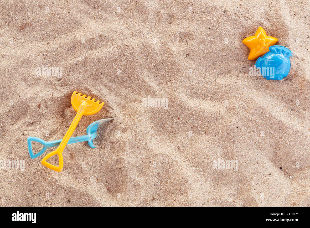 Bright plastic children's toys in the sand. Concept of beach recreation for children. Children's summer games. Summer concept. Flat lay, top view, copy space, blue and yellow. Stock Photo