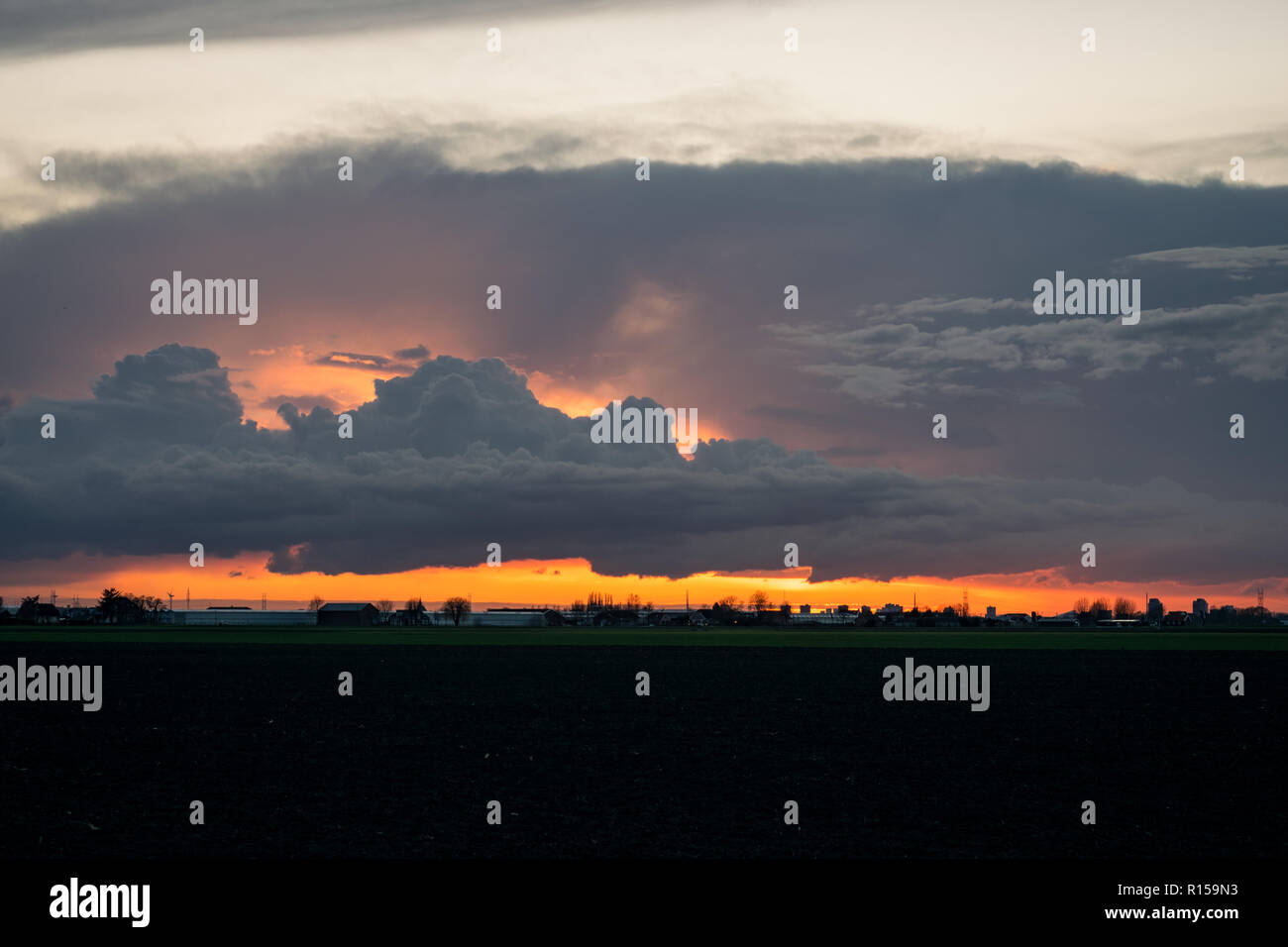 Growing cumulus clouds over the dutch countryside at sunset Stock Photo