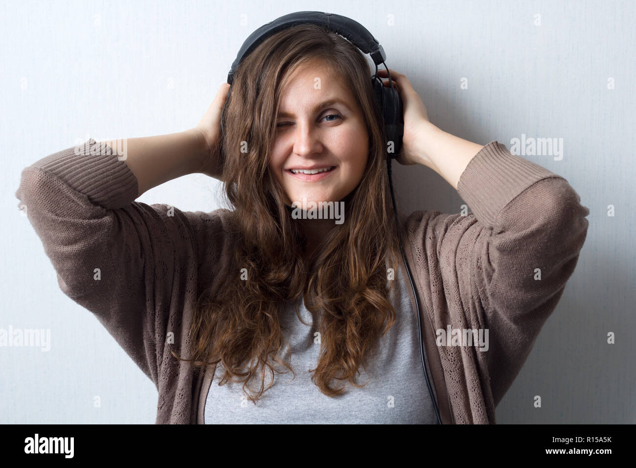 young beautiful  caucasian woman with curly hair in sweater with headphones listen and enjoy favourite music , music lover, music fan lifestyle female Stock Photo