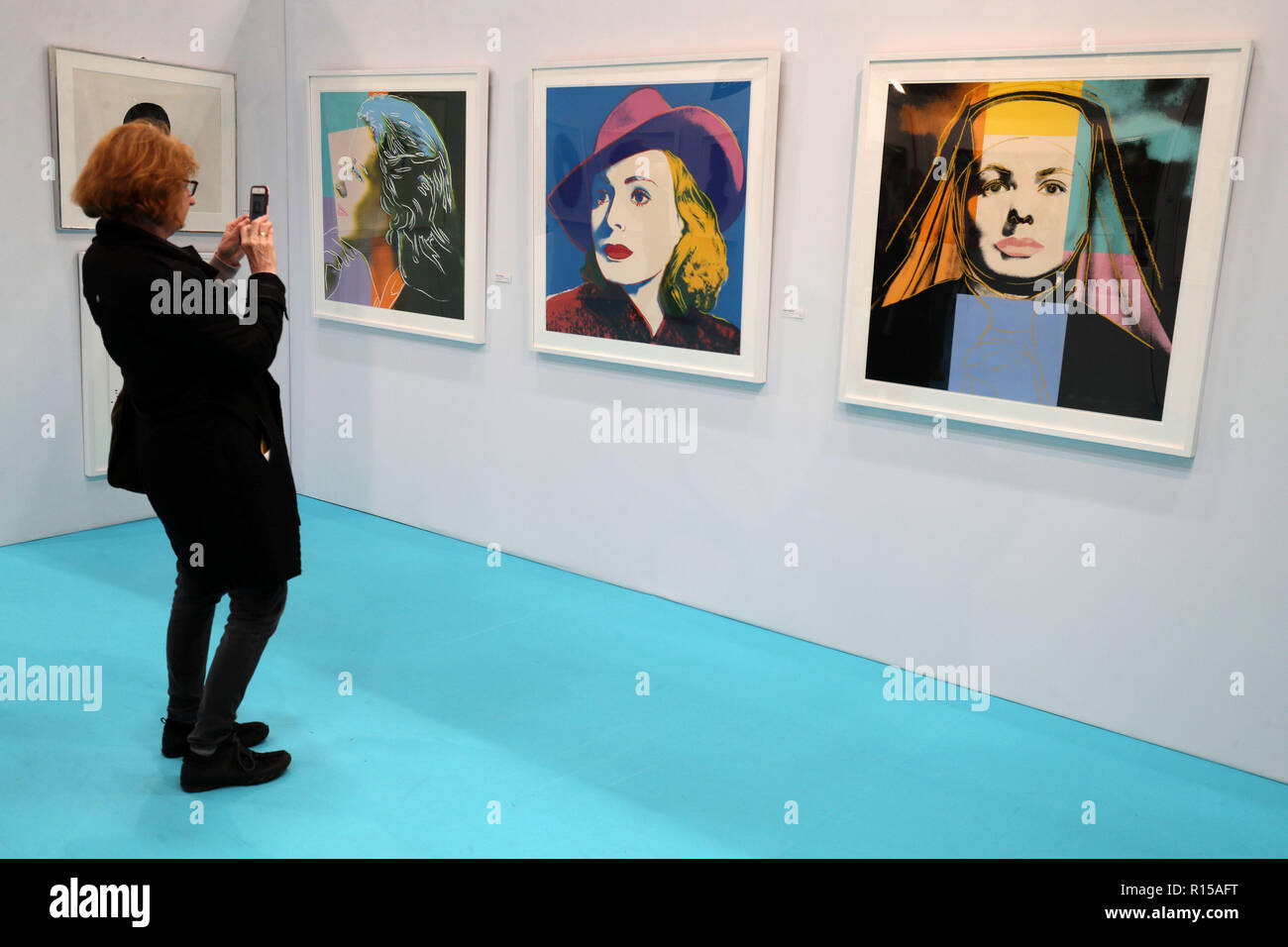 A woman takes a picture of a rare iconic collection of Ingrid Bergman  prints by Andy Warhol. The Bergman portfolio consists of 'Herself' (left), ' Bergman with Hat' (centre) and 'Ingrid The Nun'
