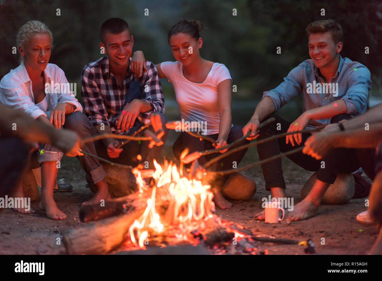 a group of happy young friends relaxing and enjoying summer evening ...