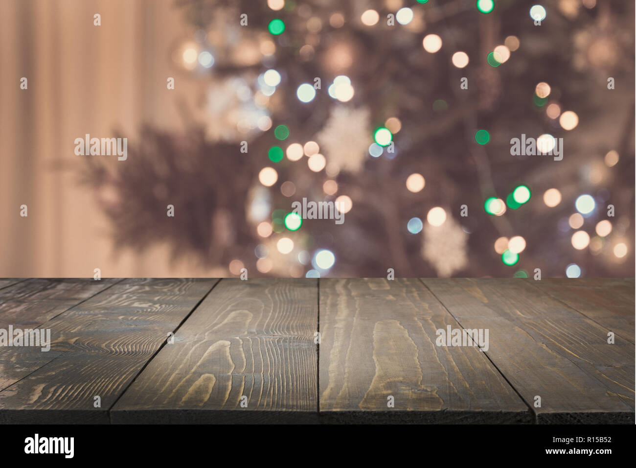 Wooden tabletop and blurred christmas tree in interior. Xmas background for display your products. Stock Photo