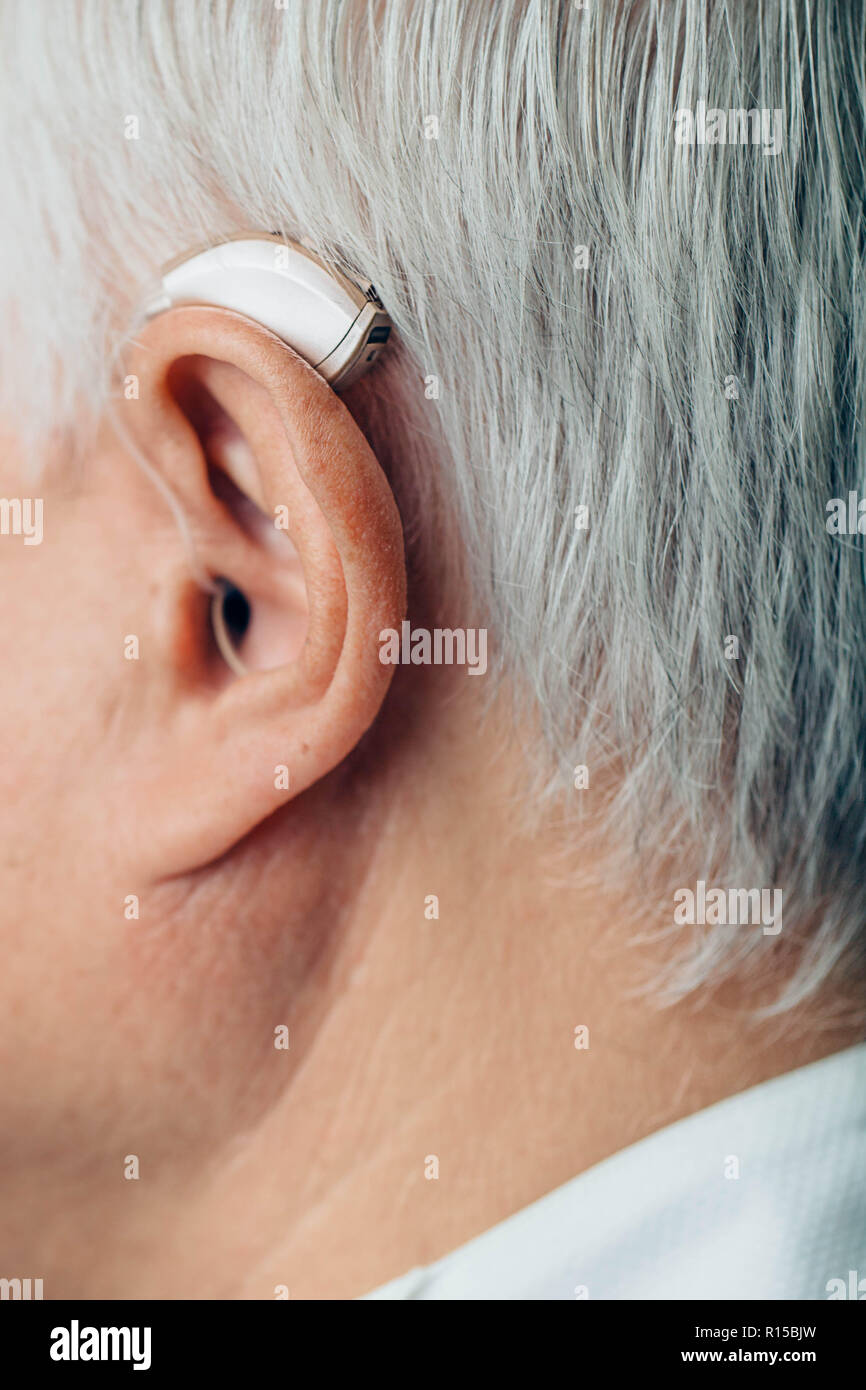 Treatment of hearing of senior man using a hearing aid, ear close-up Stock Photo