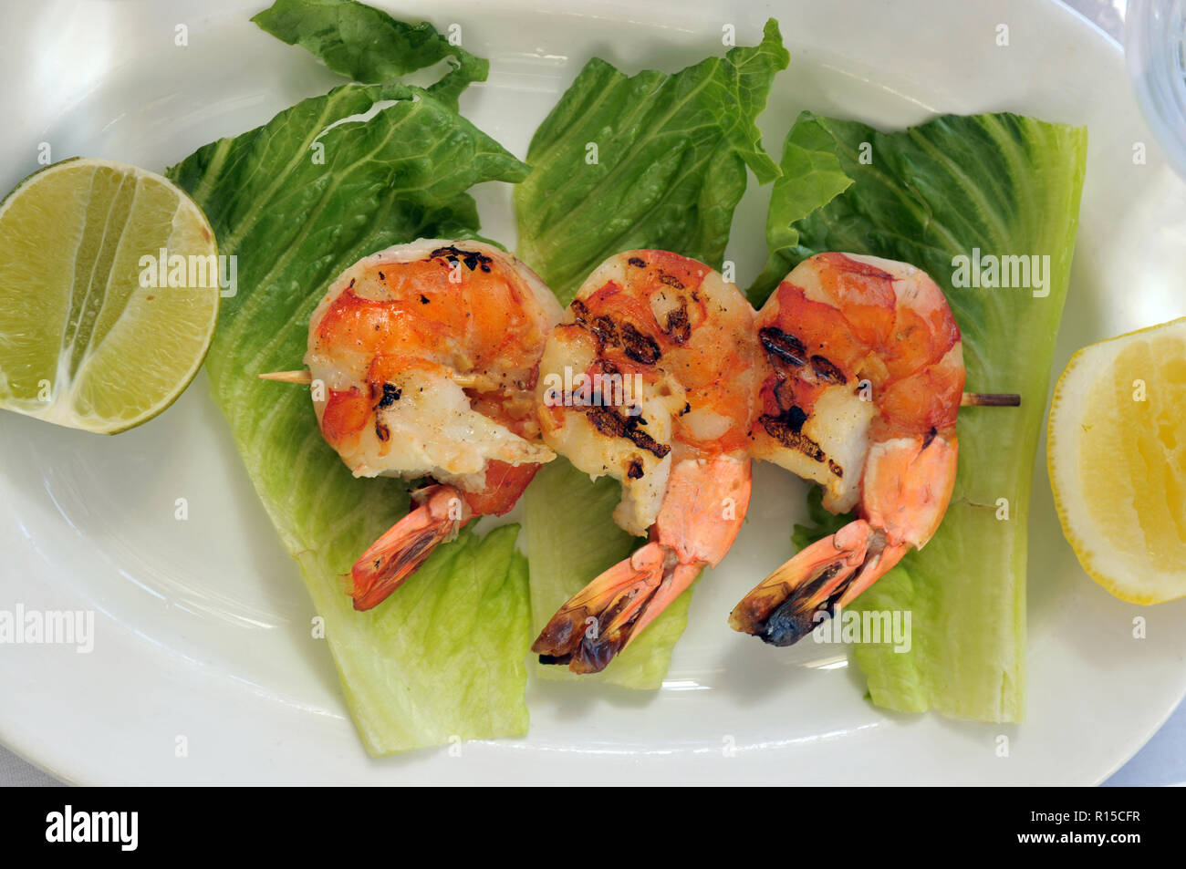 Jumbo shrimps on skewer with sweet garlic chili sauce on white plate