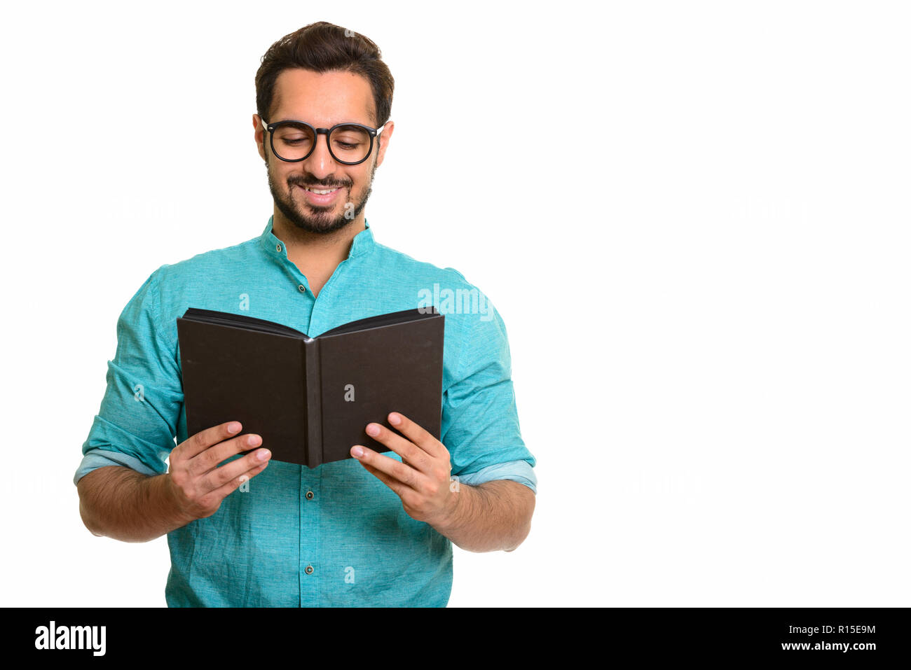Portrait of young happy Indian man reading book Stock Photo