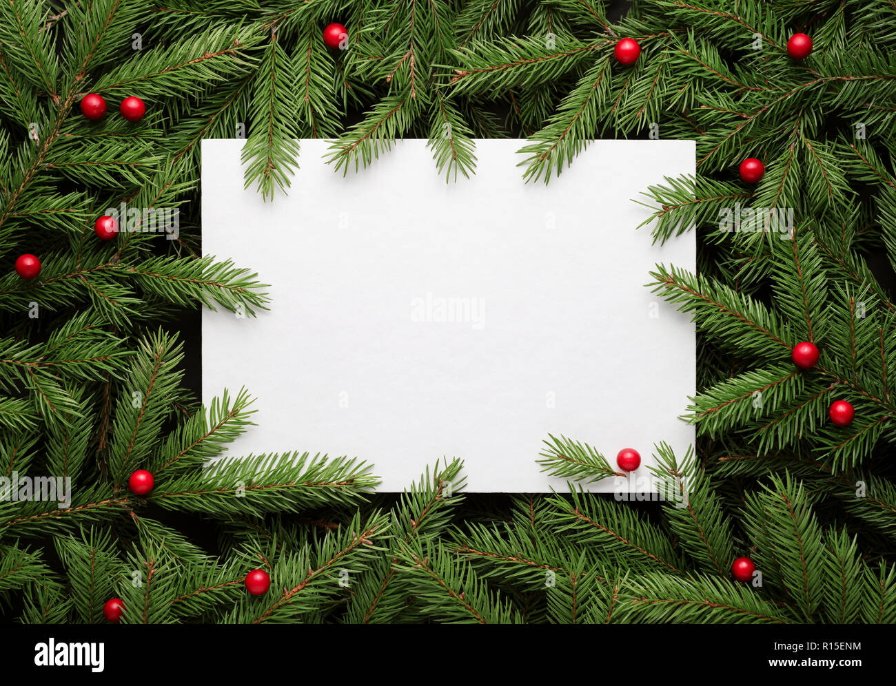 Christmas card background. Paper notice sheet with copy space for text.  Decorative frame of fir branches and holly berries. Flat lay, top view Stock Photo