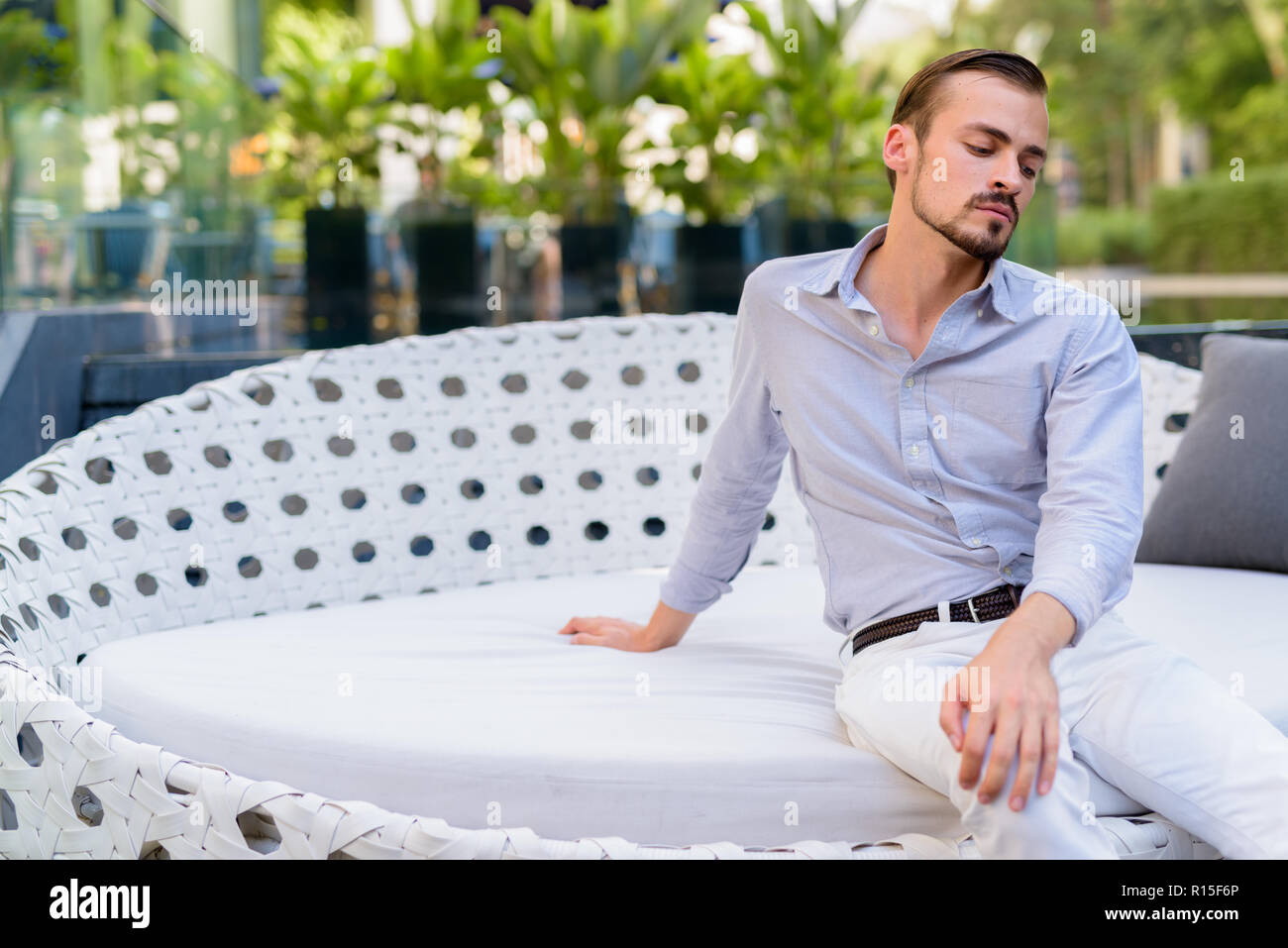 Portrait of young bearded fashionable man sitting outdoors Stock Photo