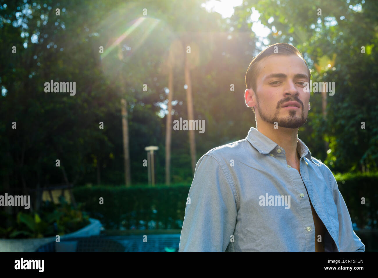 Portrait of young bearded fashionable man outdoors with lens flare Stock Photo