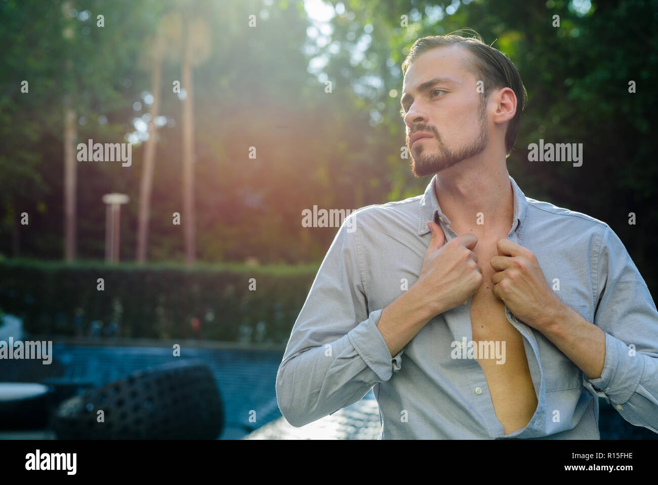 Portrait of young bearded fashionable man outdoors with lens flare Stock Photo