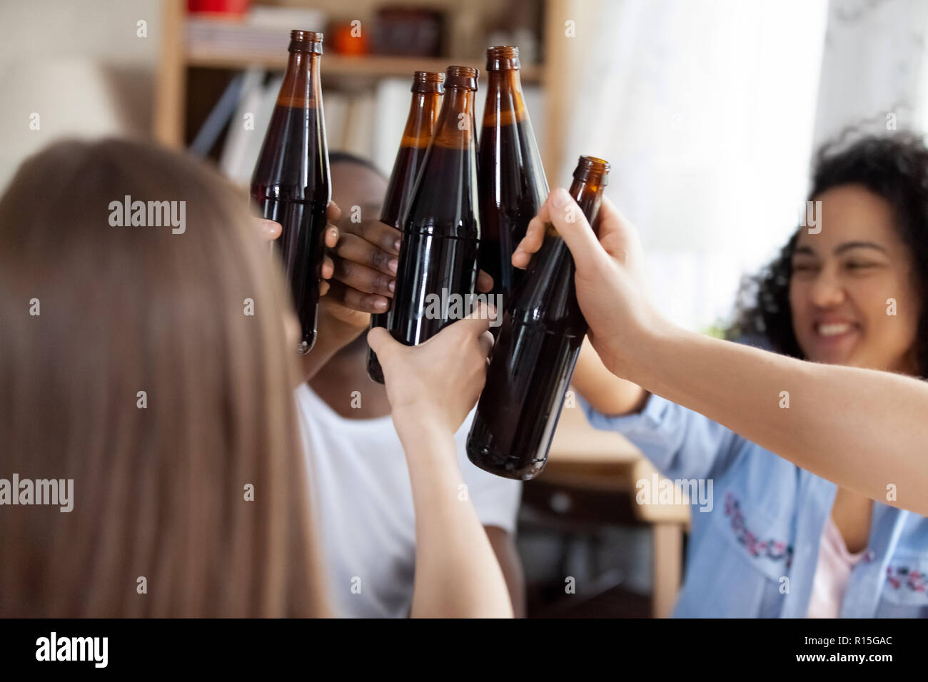 Diverse people gathered together in pub. Happy cheerful millennial multiracial best friends toasting clinking with beers celebrating special occasion, Stock Photo