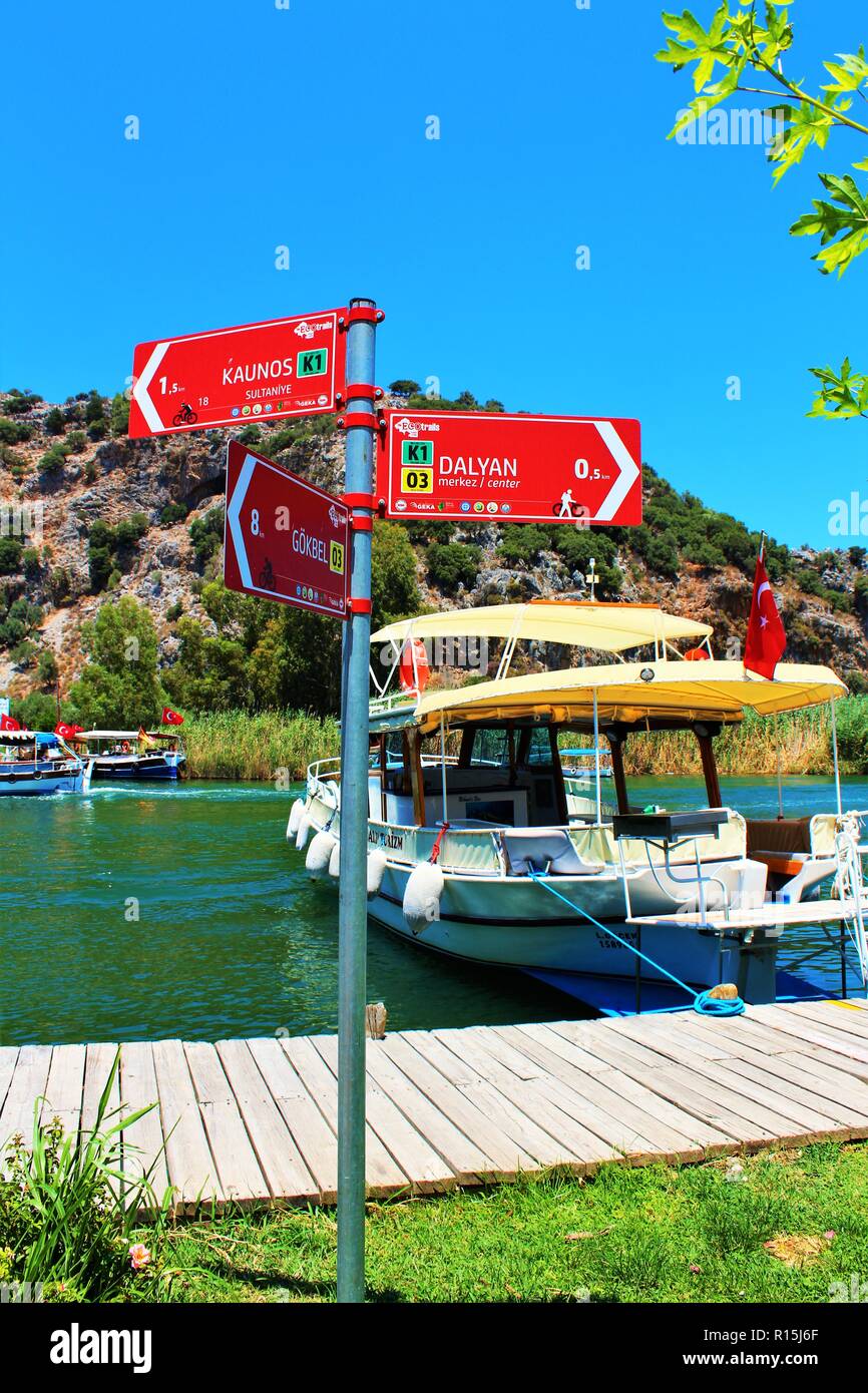 Dalyan, Turkey - July 7th 2018: A signpost pointing to the Kaunos ruins and Dalyan town, by the river Cayi, popular with passenger boats. Stock Photo