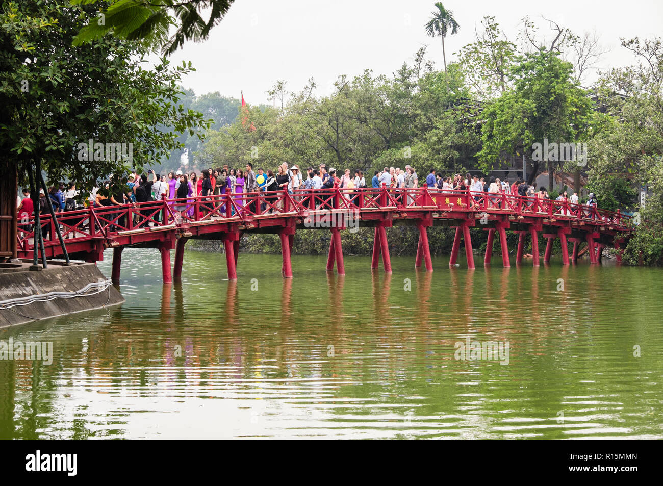 Wooden red Huc bridge to Ngoc Son Temple busy with tourists visiting Hoan Kiem lake. Hanoi, Vietnam, Asia Stock Photo