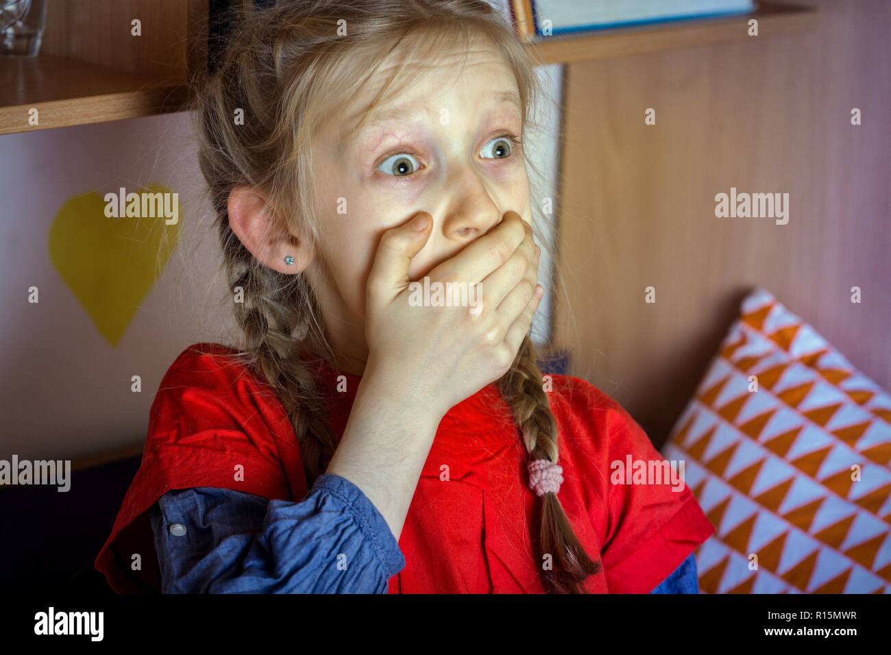 harm from watching TV and news. little girl is scared watching TV Stock Photo