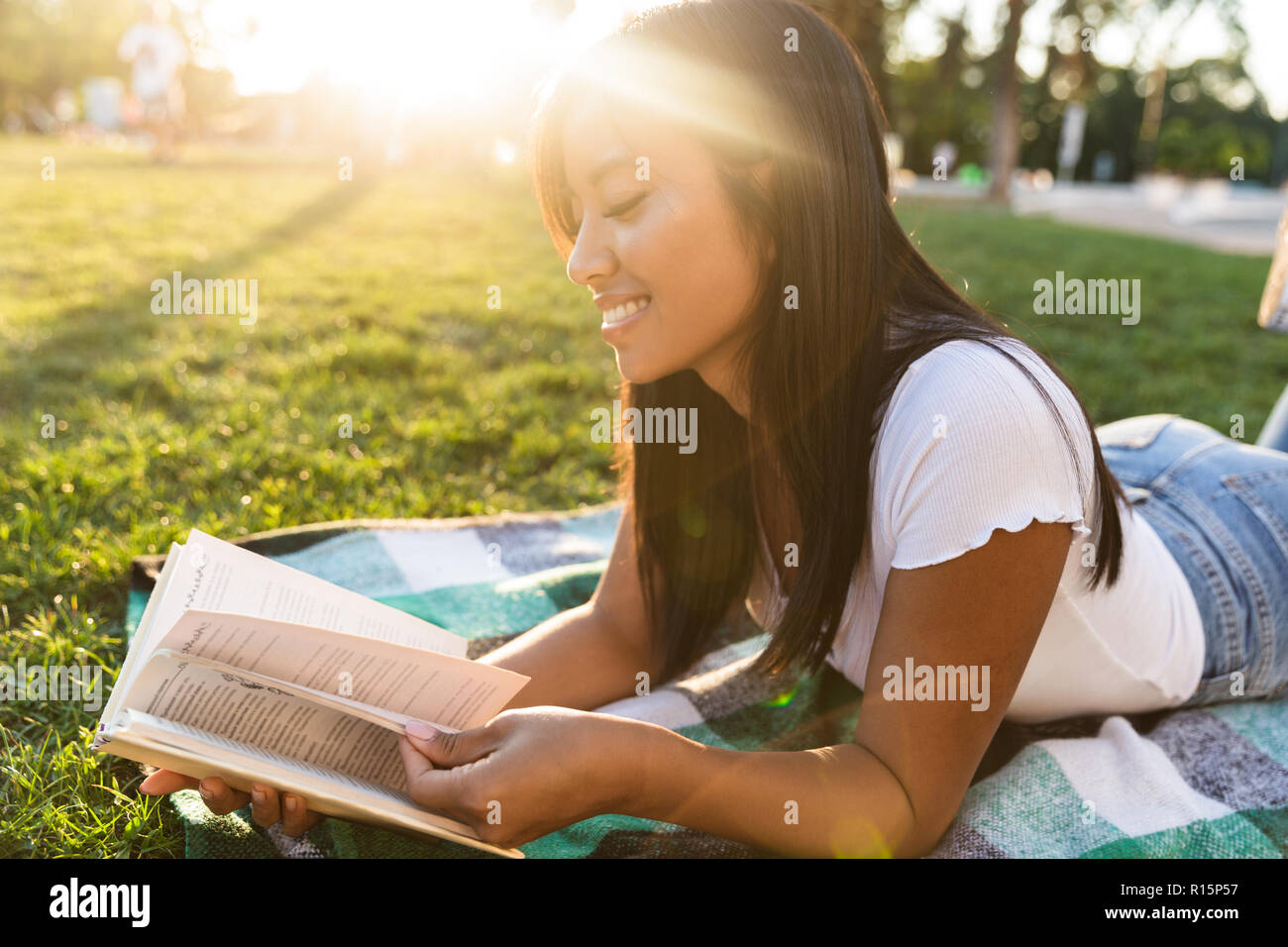 Image of happy smiling young asian girl outdoors in park reading book ...