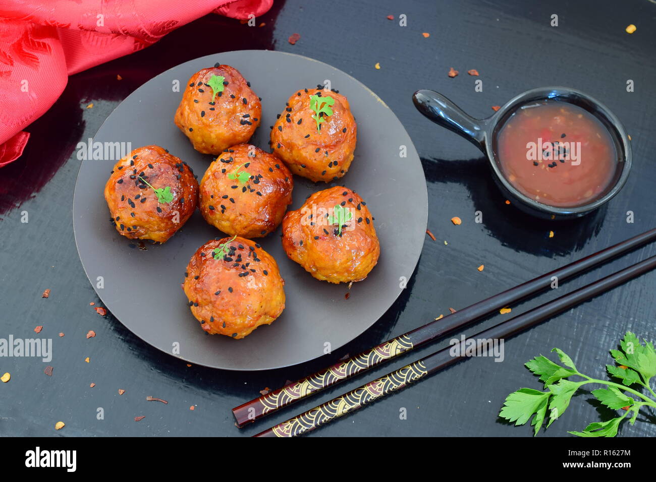 Spicy chicken balls in sweet chilly glazur on a metal tray on a black wooden background Stock Photo